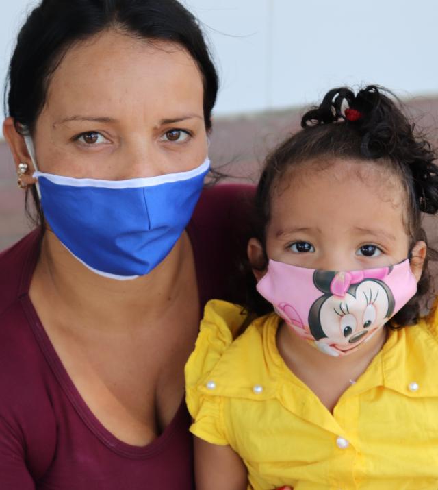 Woman and daughter from Venezuela both wearing masks.
