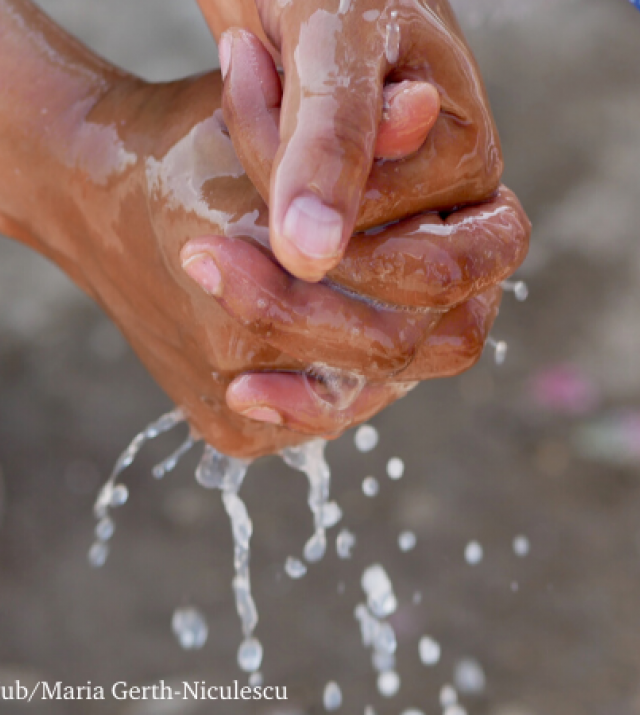Hands washing with water pouring down on them. 