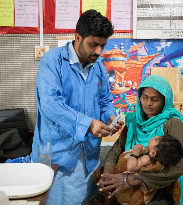 A doctor consults with a mother who is holding her young child in her arms.