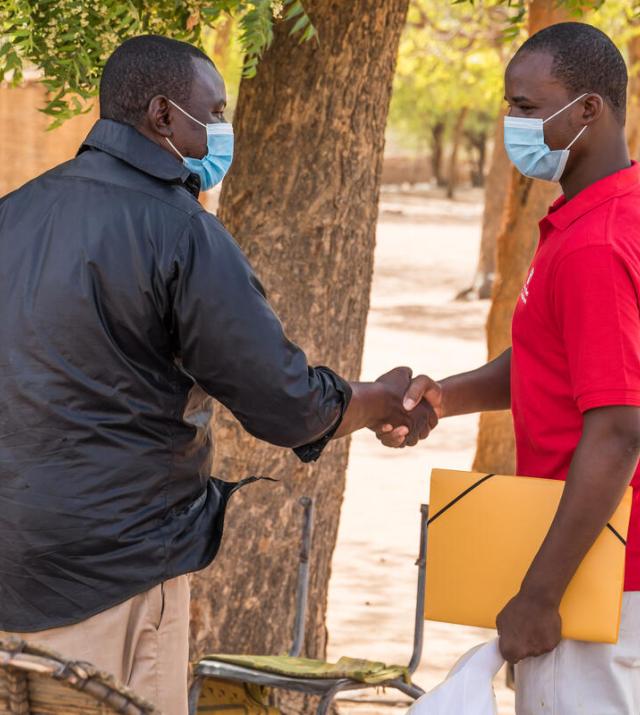 Two men wearing facemasks shaking hands.