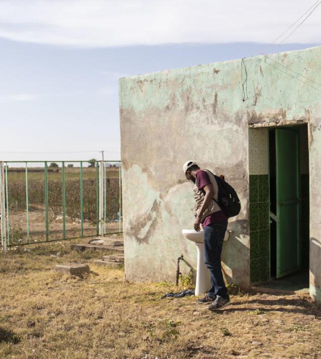 Un homme utilise un lavabo et un robinet à l’extérieur des toilettes au Soudan.