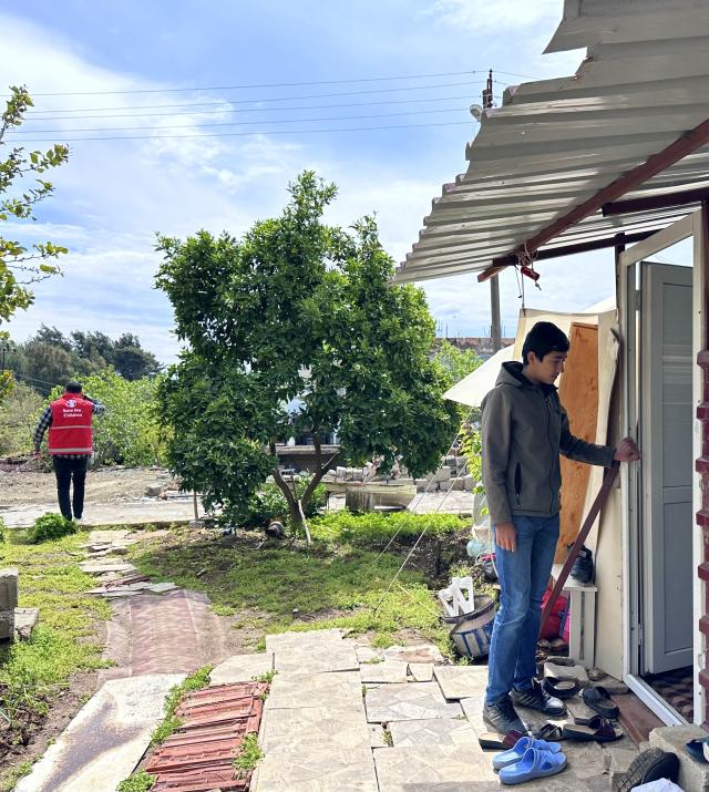 Un adolescent se tient devant un abri suite à un tremblement de terre.