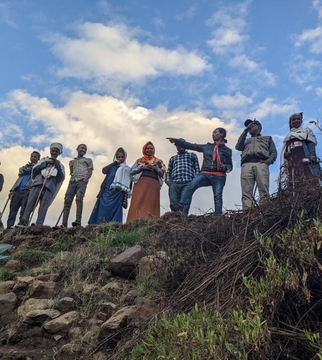 A group of people standing at the edge of a ditch 