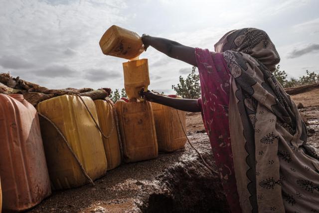 A woman pulls water out of a hole in the bed of a dried river in the Somali Region, June 28, 2019.