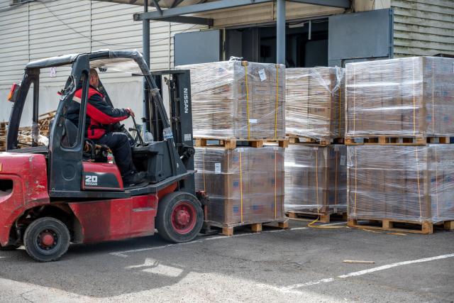 A man driving a forklift moves boxes of food aid stacked on pallets