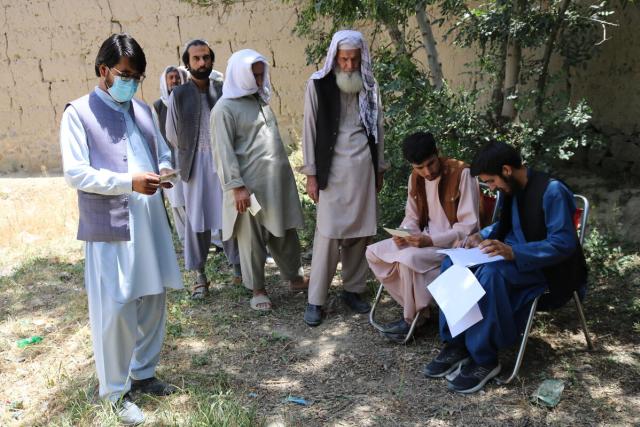 Four men line up to receive cash voucher assistance in Afghanistan