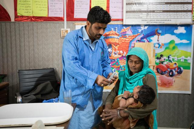 A doctor consults with a mother who is holding her young child in her arms.